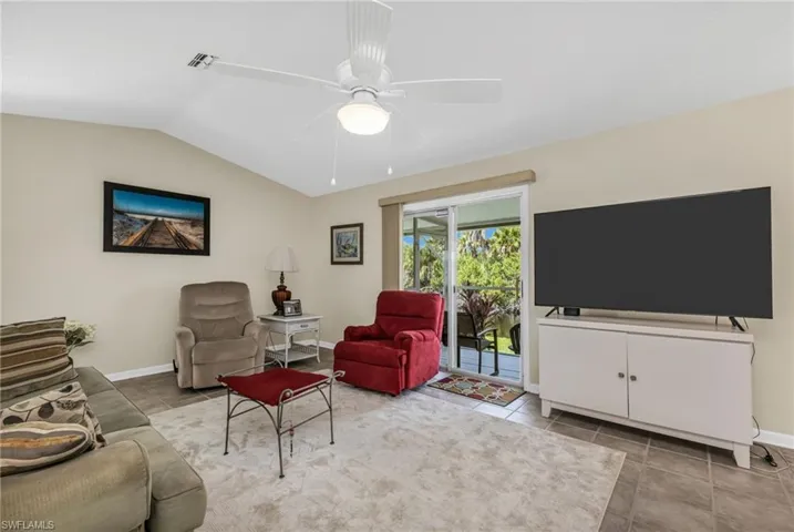 Living room with vaulted ceiling, a ceiling fan, and light tile patterned flooring
