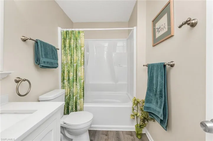 Full bath with vanity, shower / bath combo with shower curtain, a textured ceiling, and wood finished floors