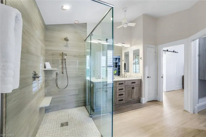 Bathroom featuring hardwood / wood-style flooring, vanity, ceiling fan, and a shower with door