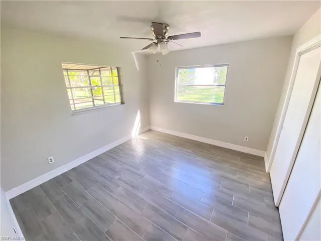 Unfurnished bedroom with a ceiling fan, multiple windows, wood finish floors, and a closet