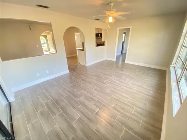 Spare room with arched walkways, ceiling fan, and wood finish floors