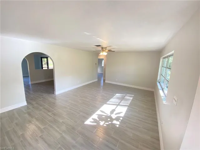Unfurnished room with wood finish floors, arched walkways, and a ceiling fan