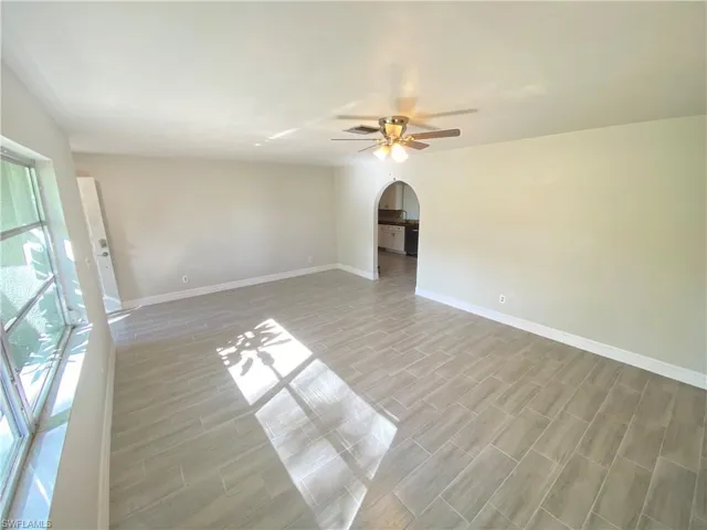 Unfurnished room featuring arched walkways, wood finish floors, and a ceiling fan