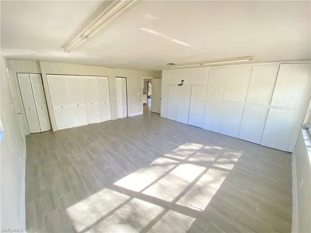 Unfurnished bedroom featuring wood tiled floors and multiple closets