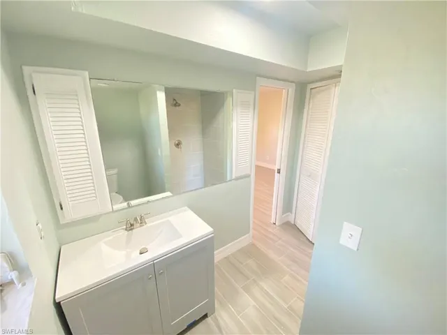 Full bath featuring a closet, vanity, a walk in shower, and wood finish floors