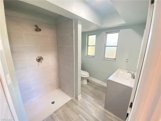 Full bathroom with vanity, a shower stall, and wood finish floors
