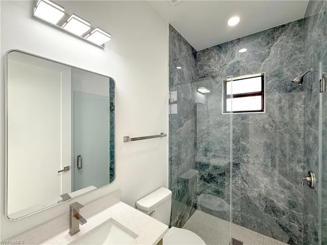Full bath with vanity, a marble finish shower, and recessed lighting