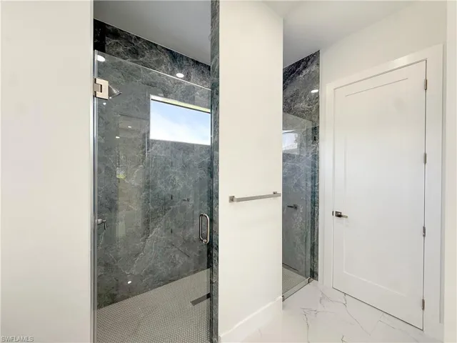 Full bath with marble look tiles and a marble finish shower