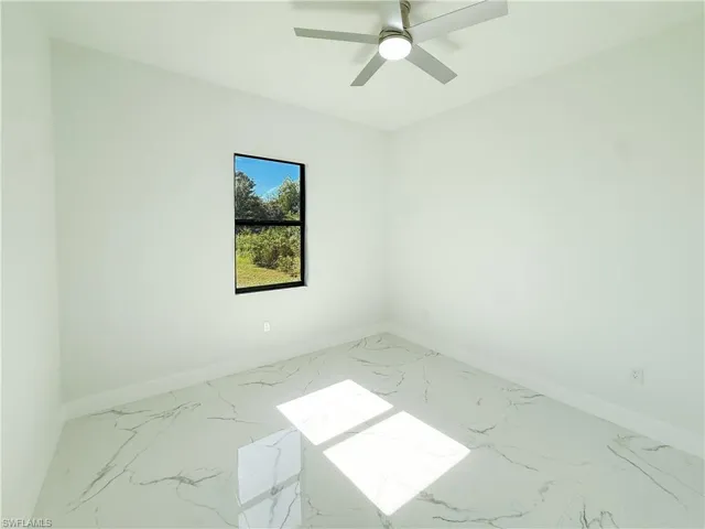 Spare room with light marble finish flooring and ceiling fan