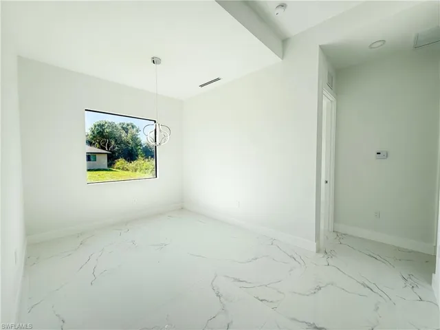 Empty room with light marble finish floors and a chandelier