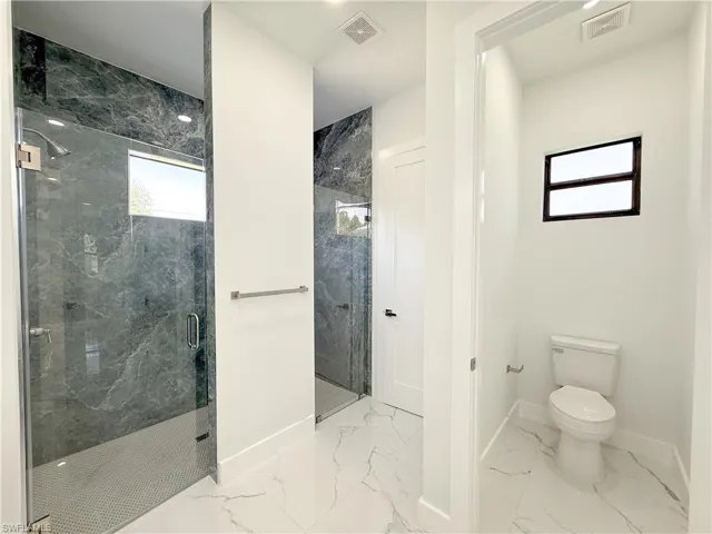 Bathroom with light marble finish floors and a marble finish shower