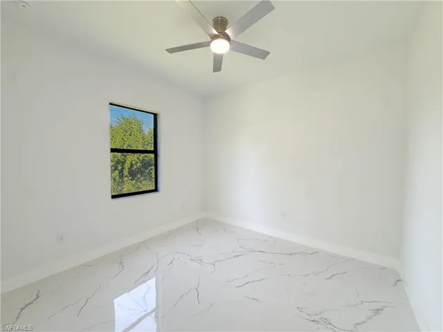 Empty room with marble finish floors and a ceiling fan