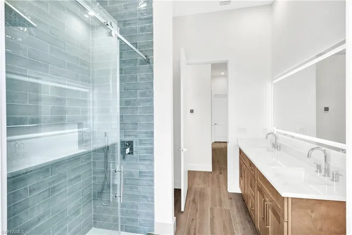 Full bathroom featuring wood finished floors, a sink, double vanity, and a shower stall
