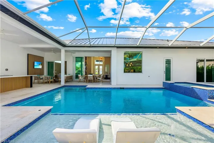 View of swimming pool with a patio, glass enclosure, outdoor dining space, and a pool with connected hot tub