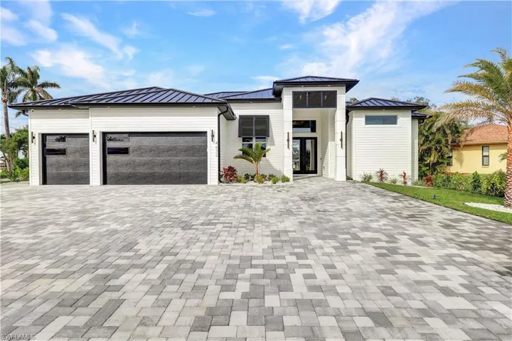 Prairie-style home featuring an attached garage, metal roof, a standing seam roof, and driveway