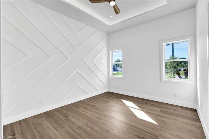Unfurnished room with baseboards, ceiling fan, and wood finished floors