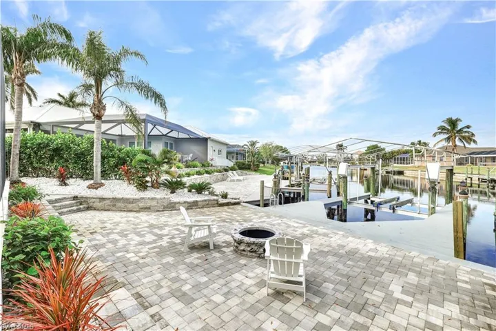 Dock featuring boat lift, a water view, an outdoor fire pit, and a patio