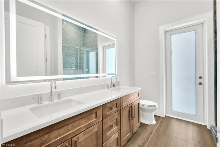 Full bath with double vanity, a sink, toilet, and a shower stall