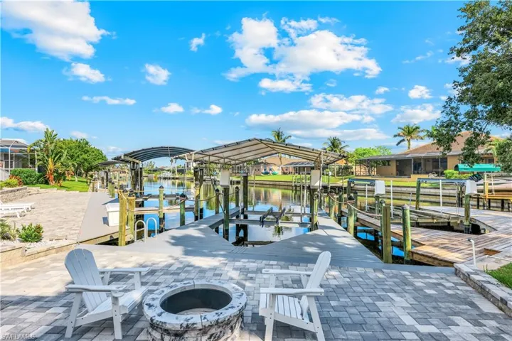Dock area featuring boat lift, an outdoor fire pit, and a water view