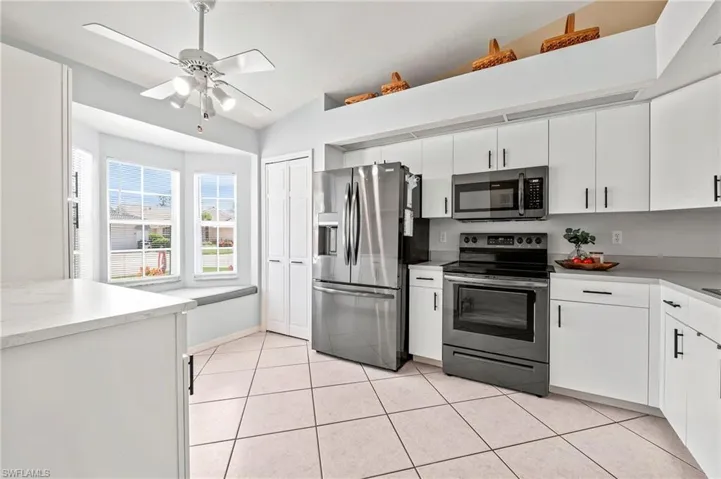 Kitchen featuring white cabinetry, light tile patterned floors, ceiling fan, and stainless steel appliances