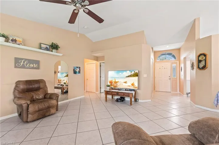 Tiled living room featuring ceiling fan and lofted ceiling