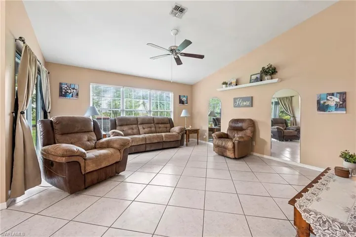 Living room with ceiling fan, lofted ceiling, and light tile patterned floors