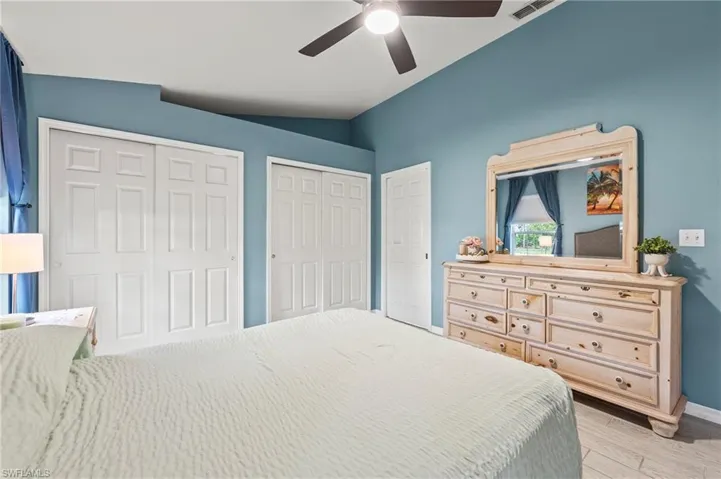 Bedroom with vaulted ceiling, multiple closets, ceiling fan, and light wood-type flooring