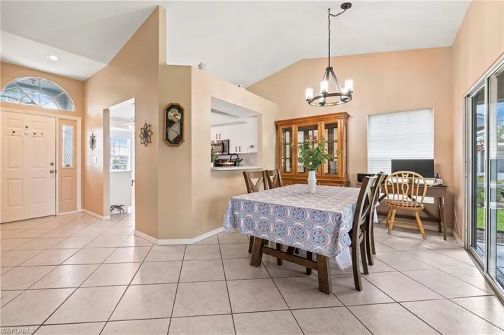 Tiled dining room with a notable chandelier, lofted ceiling, and plenty of natural light