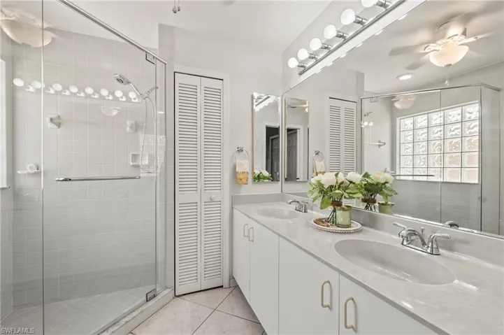 Bathroom with a shower with shower door, dual vanity, tile patterned floors, and ceiling fan