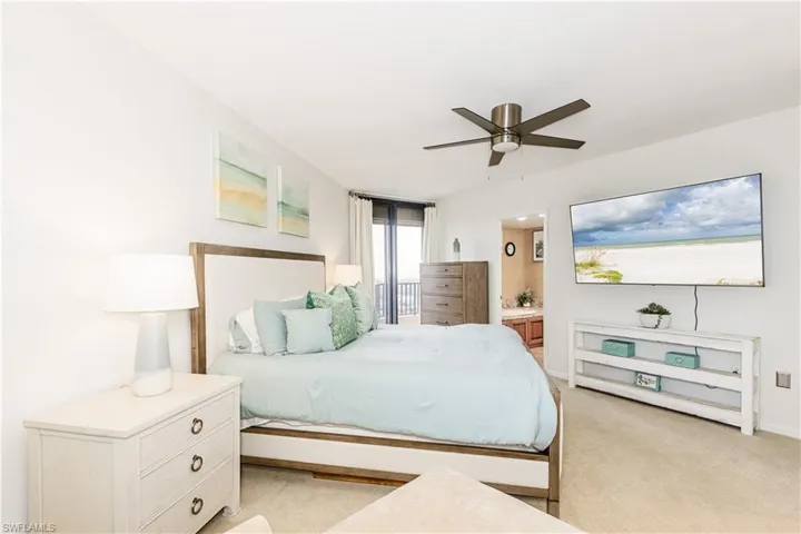 Bedroom featuring light colored carpet, connected bathroom, and ceiling fan