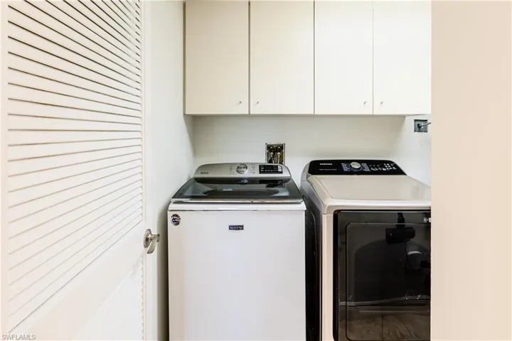 Washroom featuring washing machine and dryer and cabinets