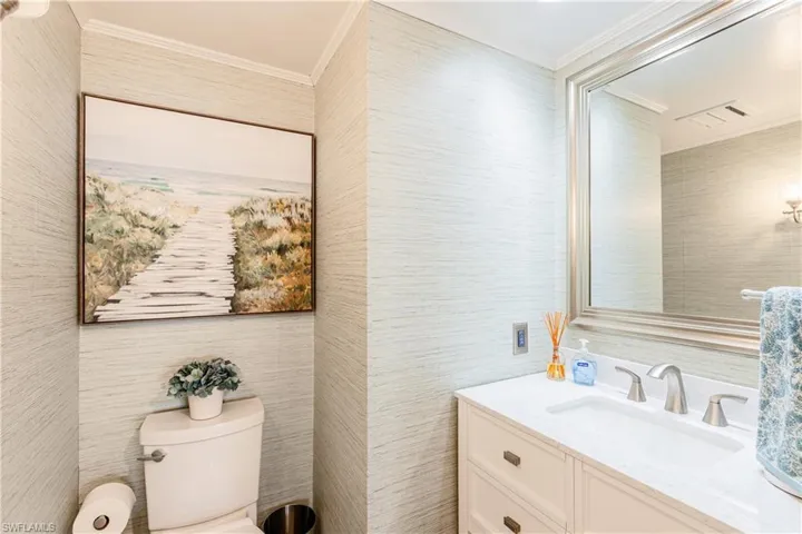 Bathroom featuring tile walls, toilet, crown molding, and vanity