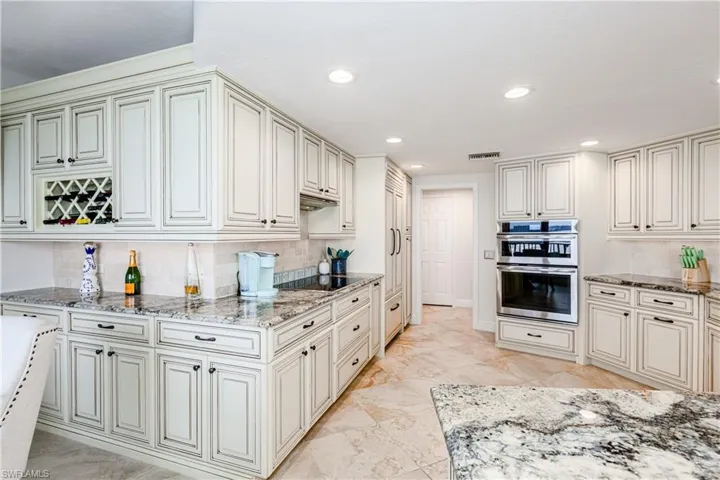 Kitchen with double oven, light tile patterned floors, decorative backsplash, and light stone counters