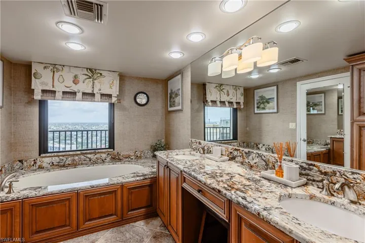 Bathroom with a washtub, double vanity, and tile patterned floors