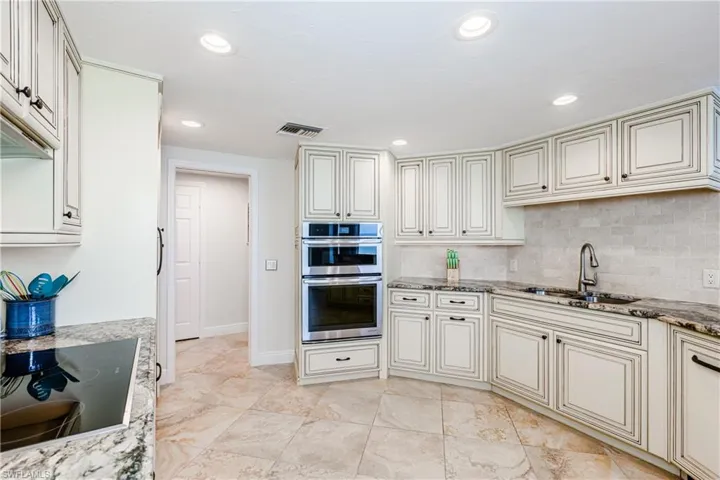 Kitchen with sink, cooktop, double oven, and light stone countertops