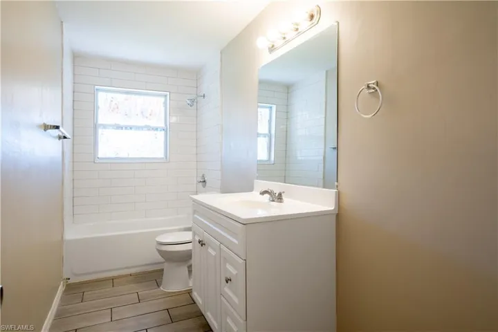 Bathroom featuring vanity, bathtub / shower combination, and wood finish floors