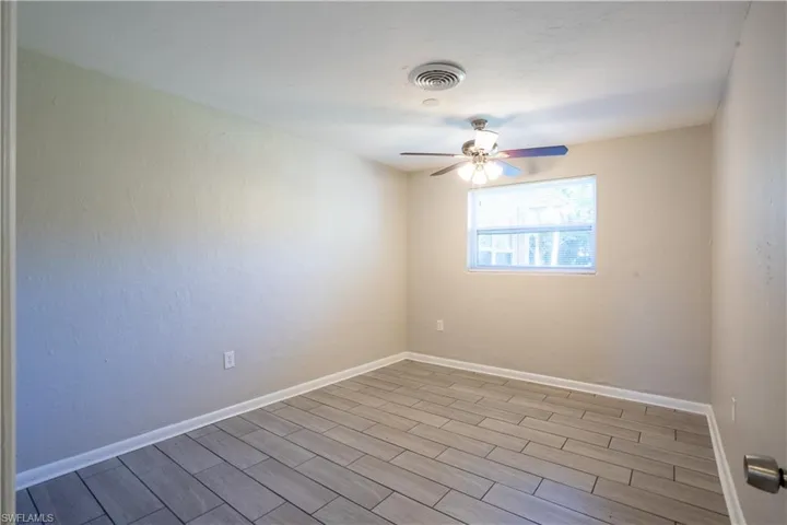 Spare room with wood finish floors, ceiling fan, and a textured wall