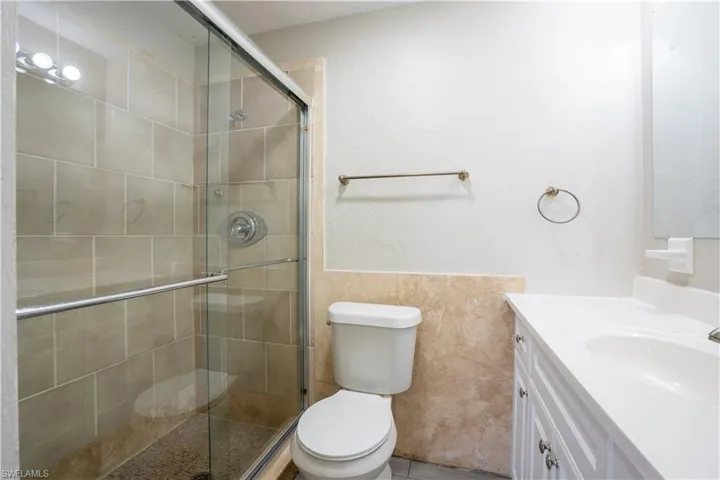 Bathroom featuring vanity, a shower stall, tile walls, and a textured wall