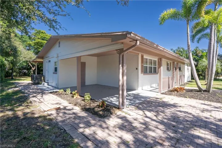 View of side of home featuring stucco siding and a carport
