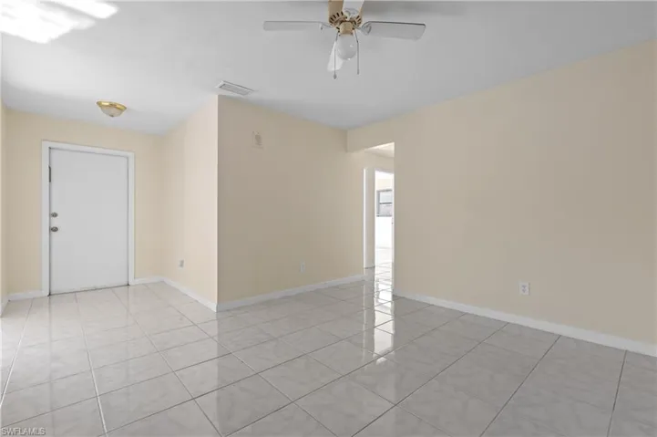 Empty room with ceiling fan and light tile patterned floors