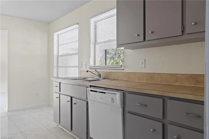 Kitchen with gray cabinetry, sink, and dishwasher
