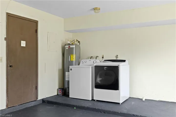 Washroom with water heater, electric panel, and washer and dryer