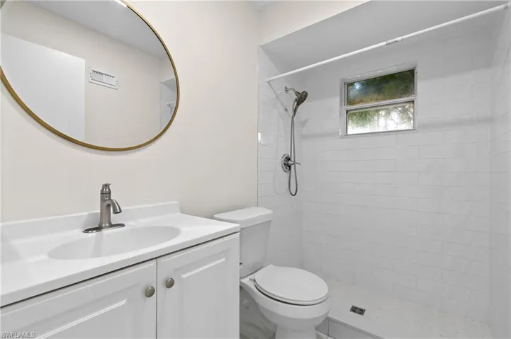 Bathroom featuring vanity, toilet, and tiled shower