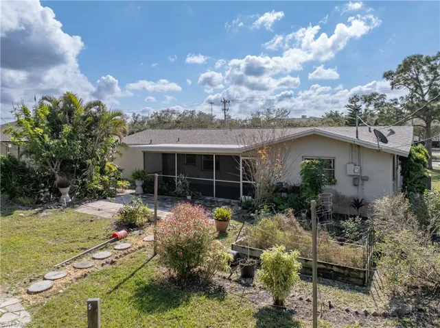 Rear view of property with a sunroom, a patio area, and a lawn