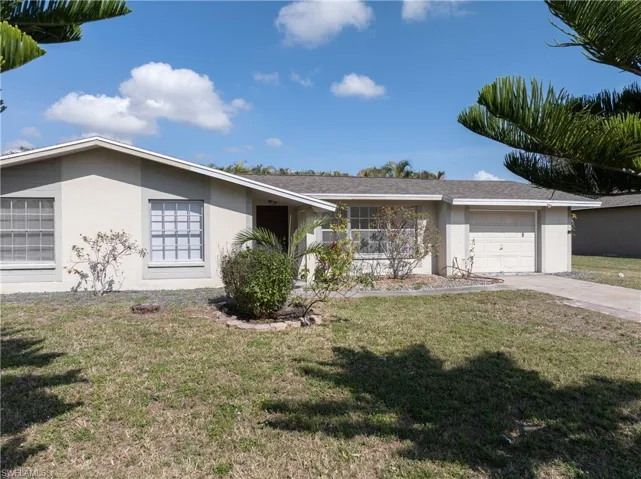 Single story home with a garage and a front yard