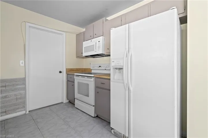 Kitchen with light tile patterned flooring and white appliances