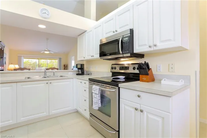 Kitchen with white cabinetry, sink, stainless steel appliances, and ceiling fan
