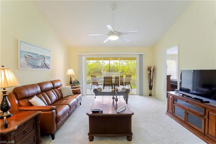 Carpeted living room with vaulted ceiling and ceiling fan