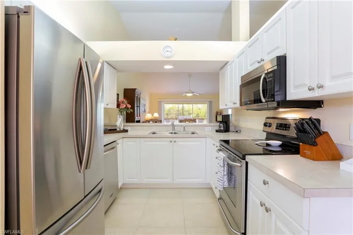 Kitchen featuring white cabinets, stainless steel appliances, sink, lofted ceiling, and kitchen peninsula