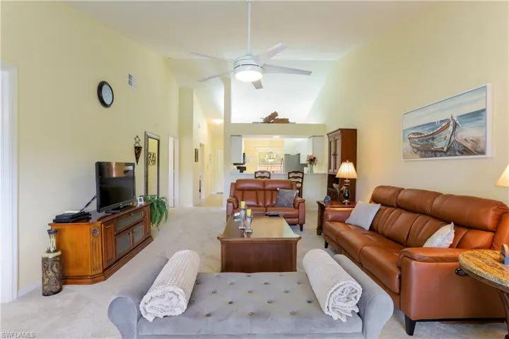 Living room featuring ceiling fan, light carpet, and high vaulted ceiling